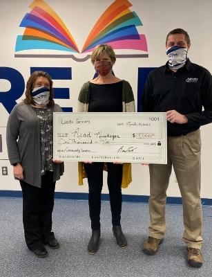 man presenting giant check to two women